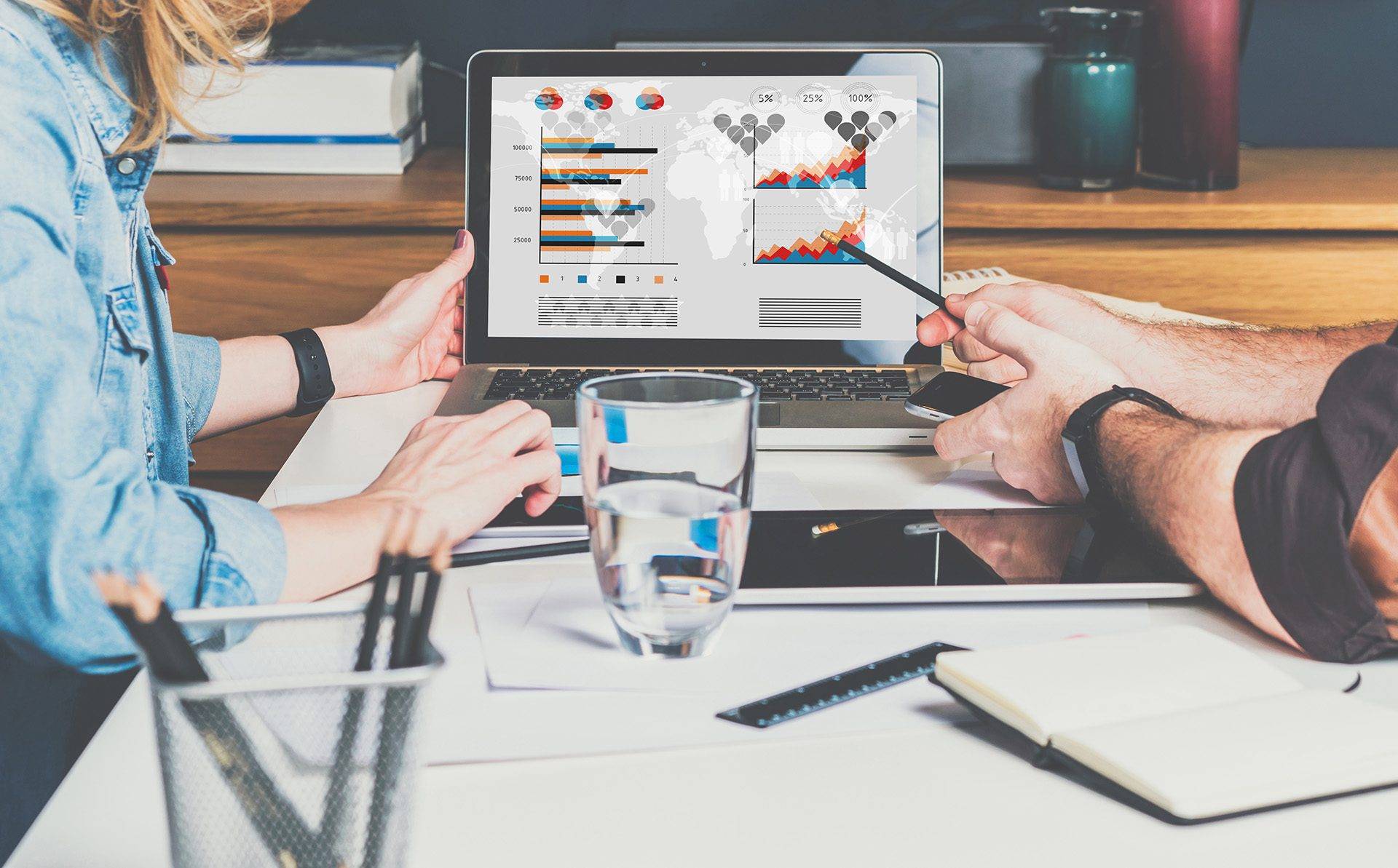 Businessman and businesswoman sitting at table in front of laptop and working. Graphs,charts and diagrams on PC screen.